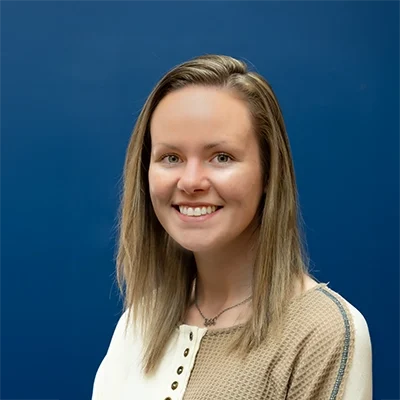 Chiropractic Oakdale MN Lauren Lauren smiling in front of a blue wall.